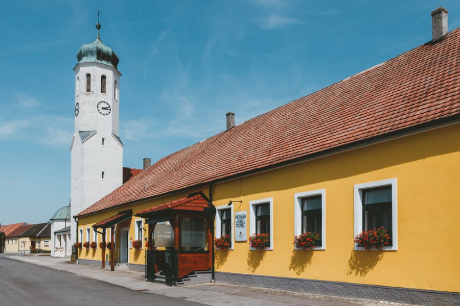 Gelbes Geb&auml;ude mit Kirchturm und blauen Himmel in einer Stadtansicht.