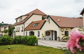 Ein traditionelles Gasthaus mit rotem Ziegeldach und gepflegtem Garten im Vordergrund.