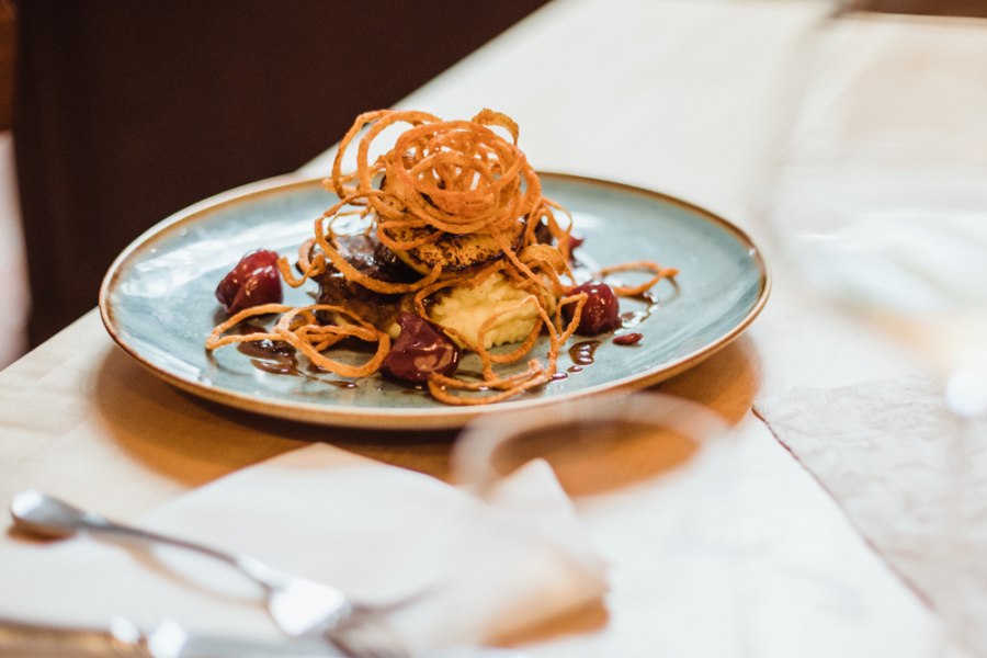 Fleischgericht mit Zwiebelringen auf Kartoffelp&uuml;ree und Sauce.