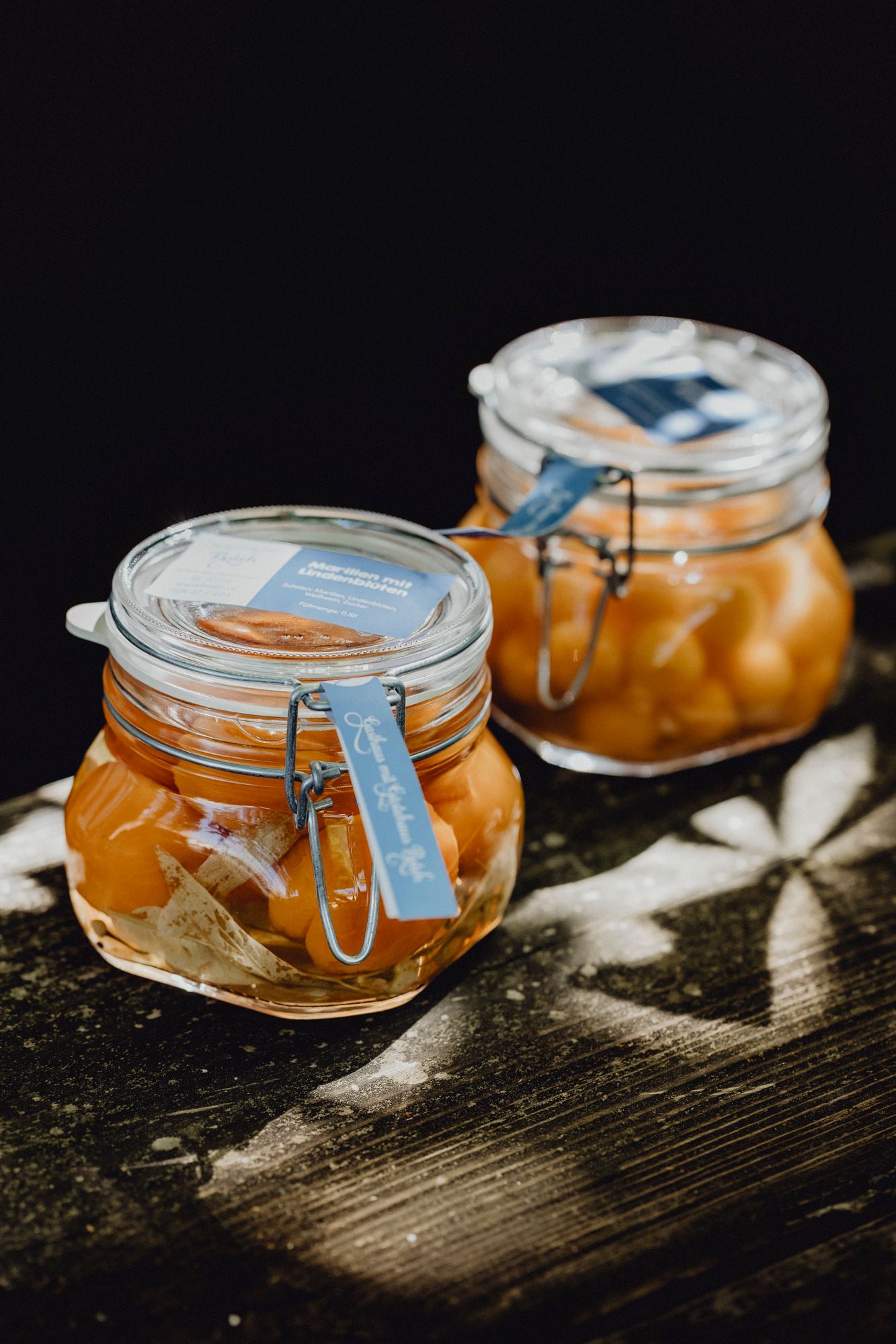 Zwei Einmachgläser mit eingelegten Früchten auf einem Holztisch.