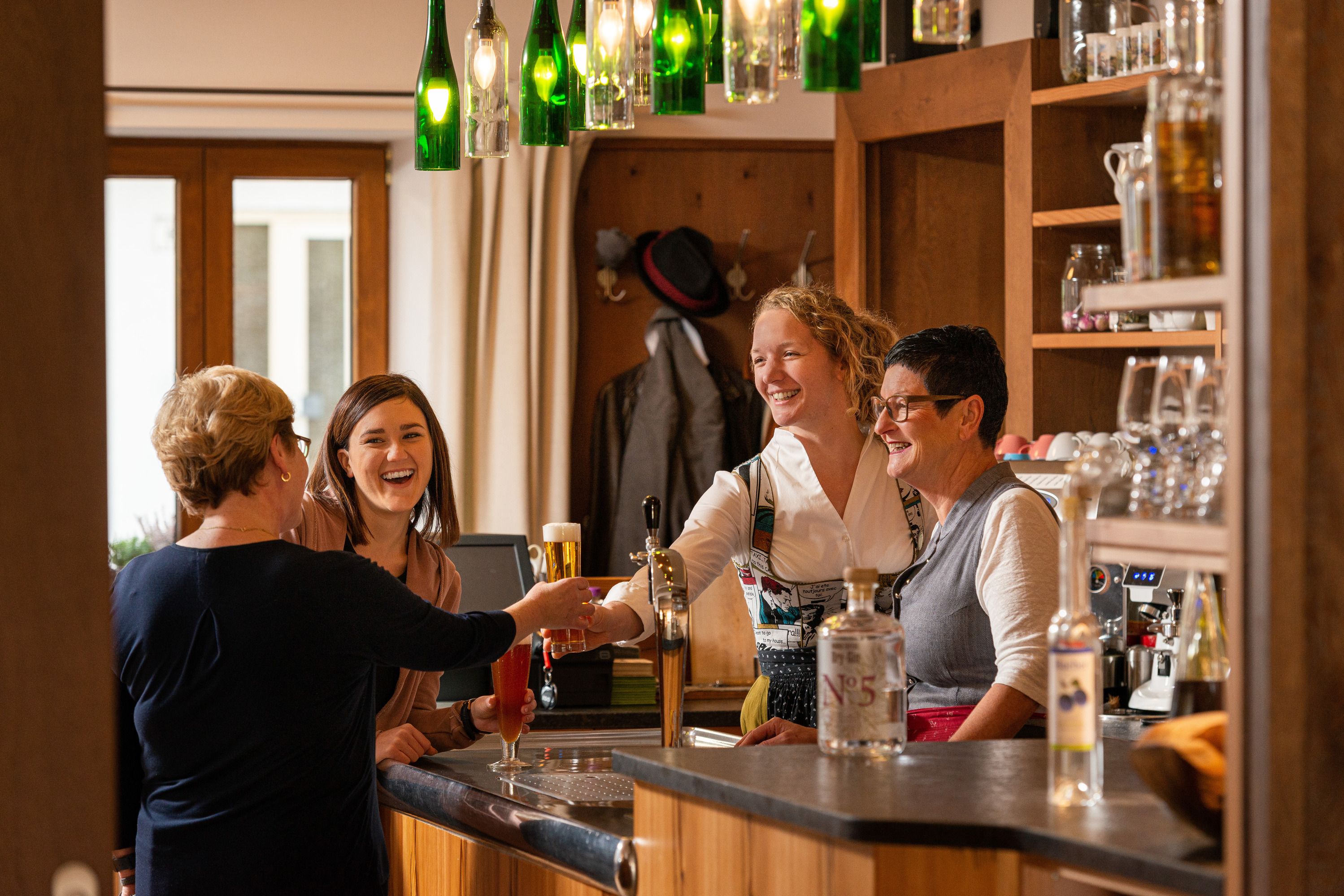 Vier Frauen lachen und unterhalten sich an einer Bar.