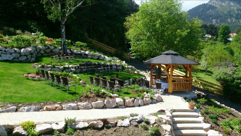 Ein gepflegter Garten mit einem Hochzeitspavillon, umgeben von St&uuml;hlen und gr&uuml;ner Landschaft.